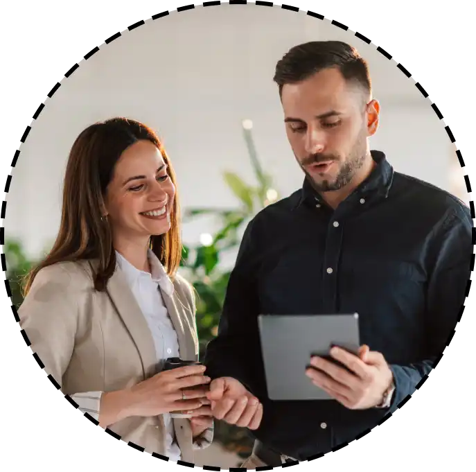 coworkers talk while holding a tablet computer