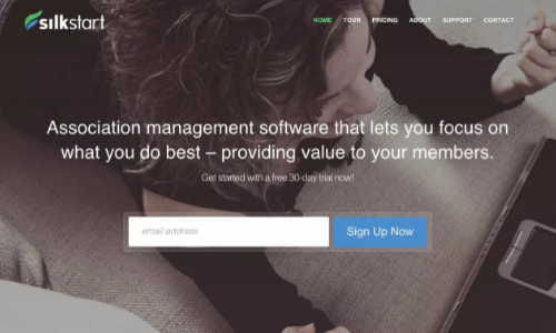 SilkStart homepage, with an email free trial signup and informative blurb against a background of a person using Silkstart on their laptop.