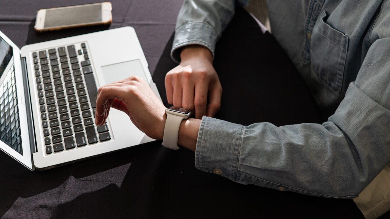 While checking in using the software on their laptop, an association member checks their smartwatch.