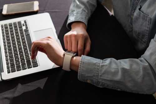 While checking in using the software on their laptop, an association member checks their smartwatch.