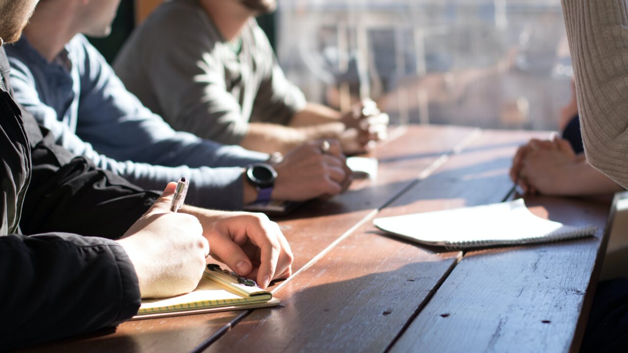 A group of people at a table, taking notes while discussing the ideal membership models.
