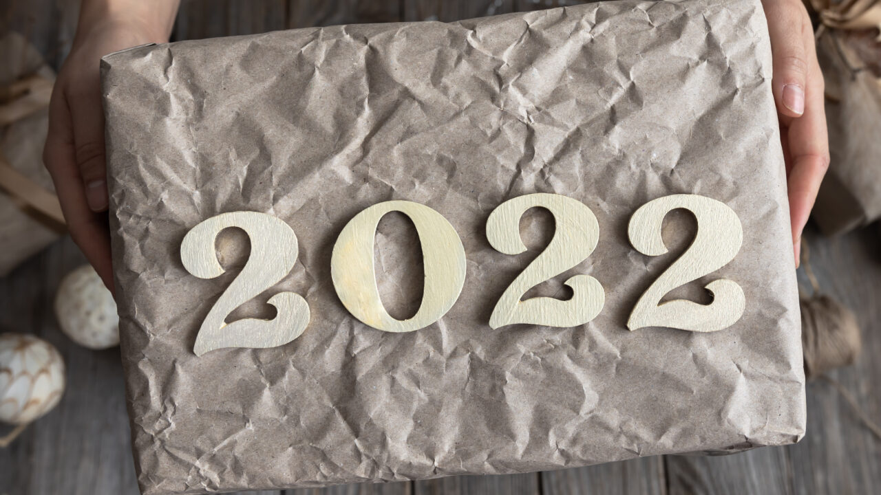 wrapped gift with 2022 on the top of it held by hands